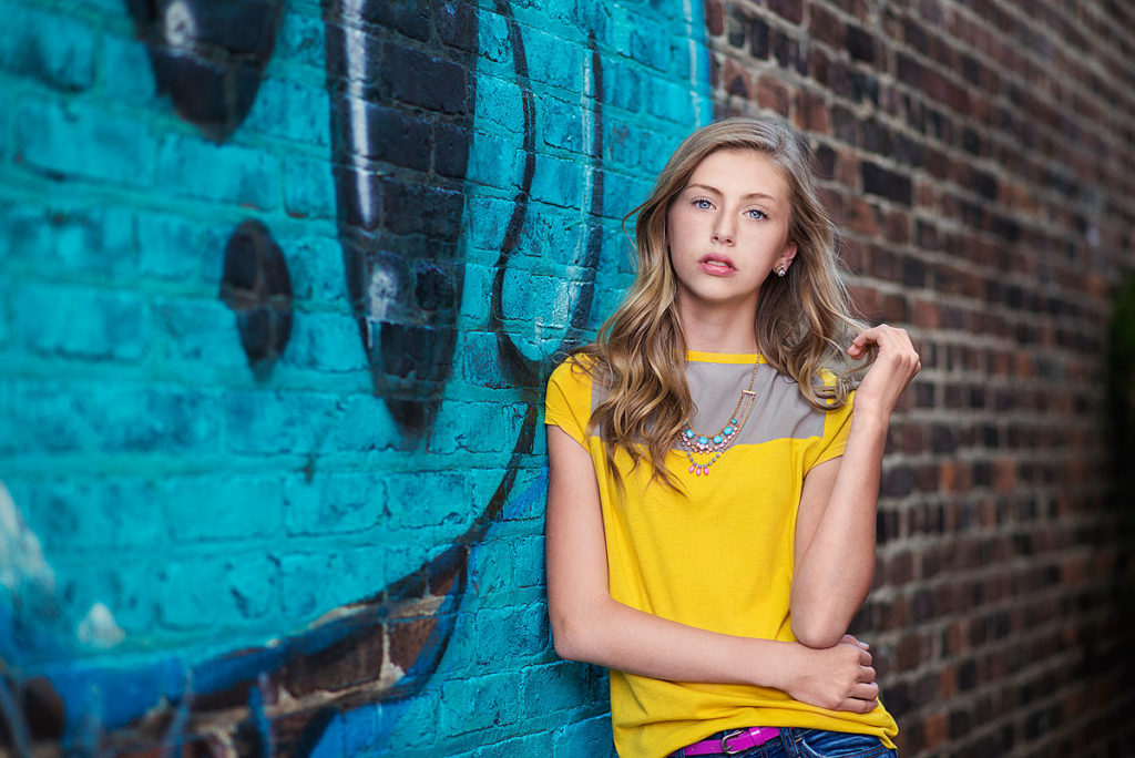 Louisville teen leaning against graffiti wall