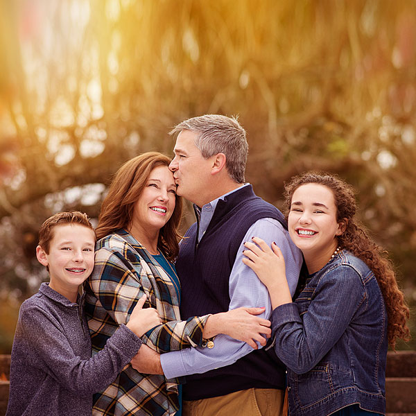 Louisville Fall Family Portrait of Dad kissing Mom and two kids by Louisville Family Photographer