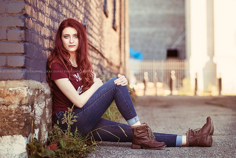 Girl sitting against blue wall for urban louisville senior pictures with Ray Davis Photography