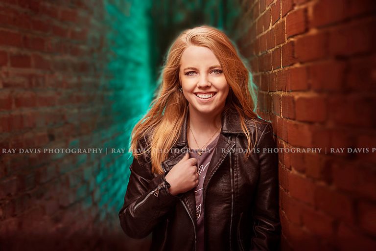 Urban senior girl standing in alleyway with off camera flash blue gels for louisville senior photographer Ray Davis Photography