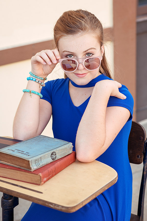 Tween Girl sitting at desk holding glasses from Louisville Tween Photographer Back To School Minisessions