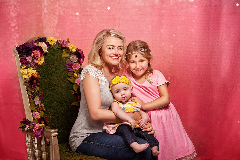 Mother with 2 daughters on pink backdrop taken by Louisville Child Photographer