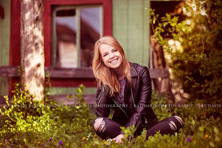 Girl wearing leather jacket sitting in grass for lagrange senior pictures with louisville photographers ray davis photography