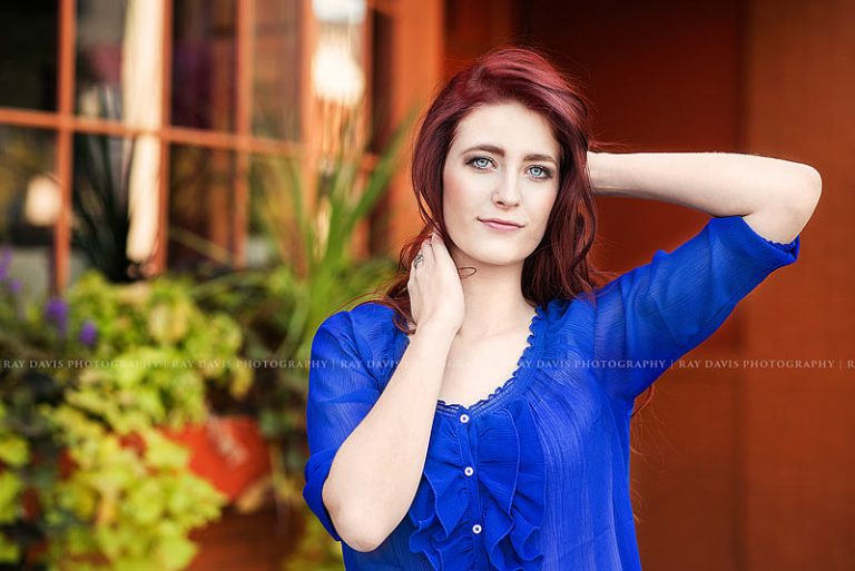 High School Senior Girl wearing blue short in front of orange background for pictures with Louisville Photographer Ray Davis Photography