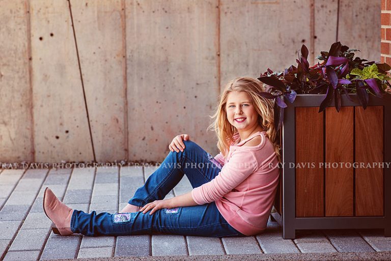 Louisville Tween pictures of girl sitting on sidewalk in pink long sleeve shirt