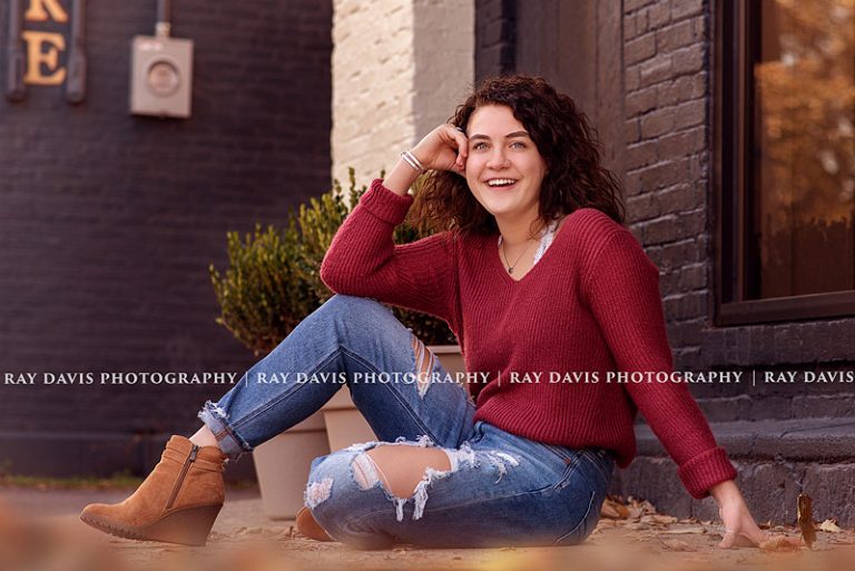 Girl sitting on ground in downtown Louisville for fall senior pictures