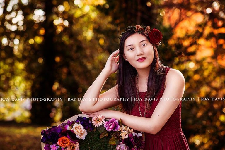 Girl leaning on moss chair with flowers for fall senior pictures