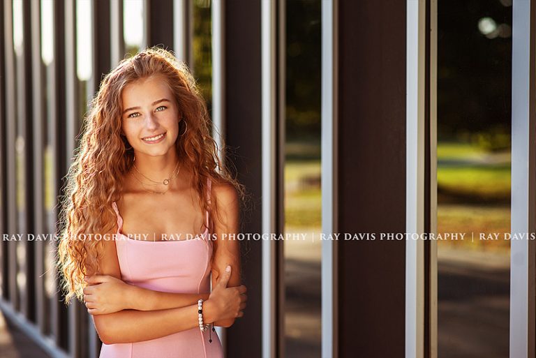 senior girl posing against library wall in east louisville in a pink dress for pictures